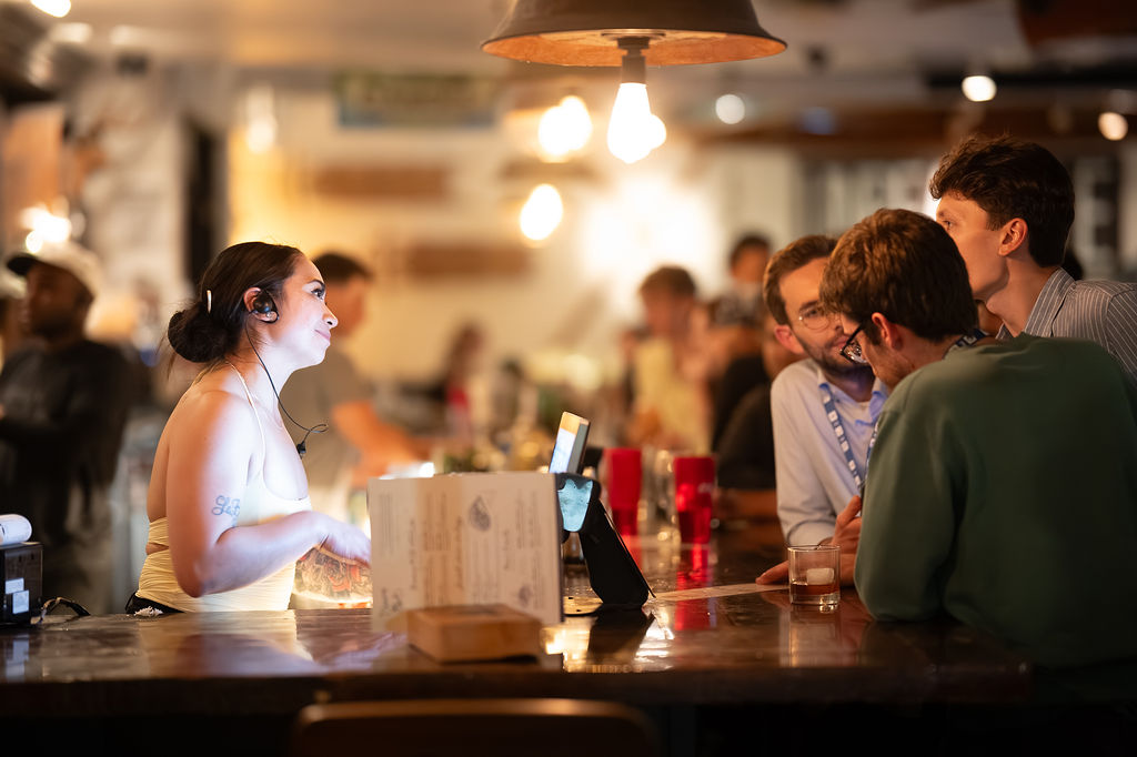 Bartender serving guests at the bar at Unbearable Skee Lodge - warm lighting and intimate atmosphere