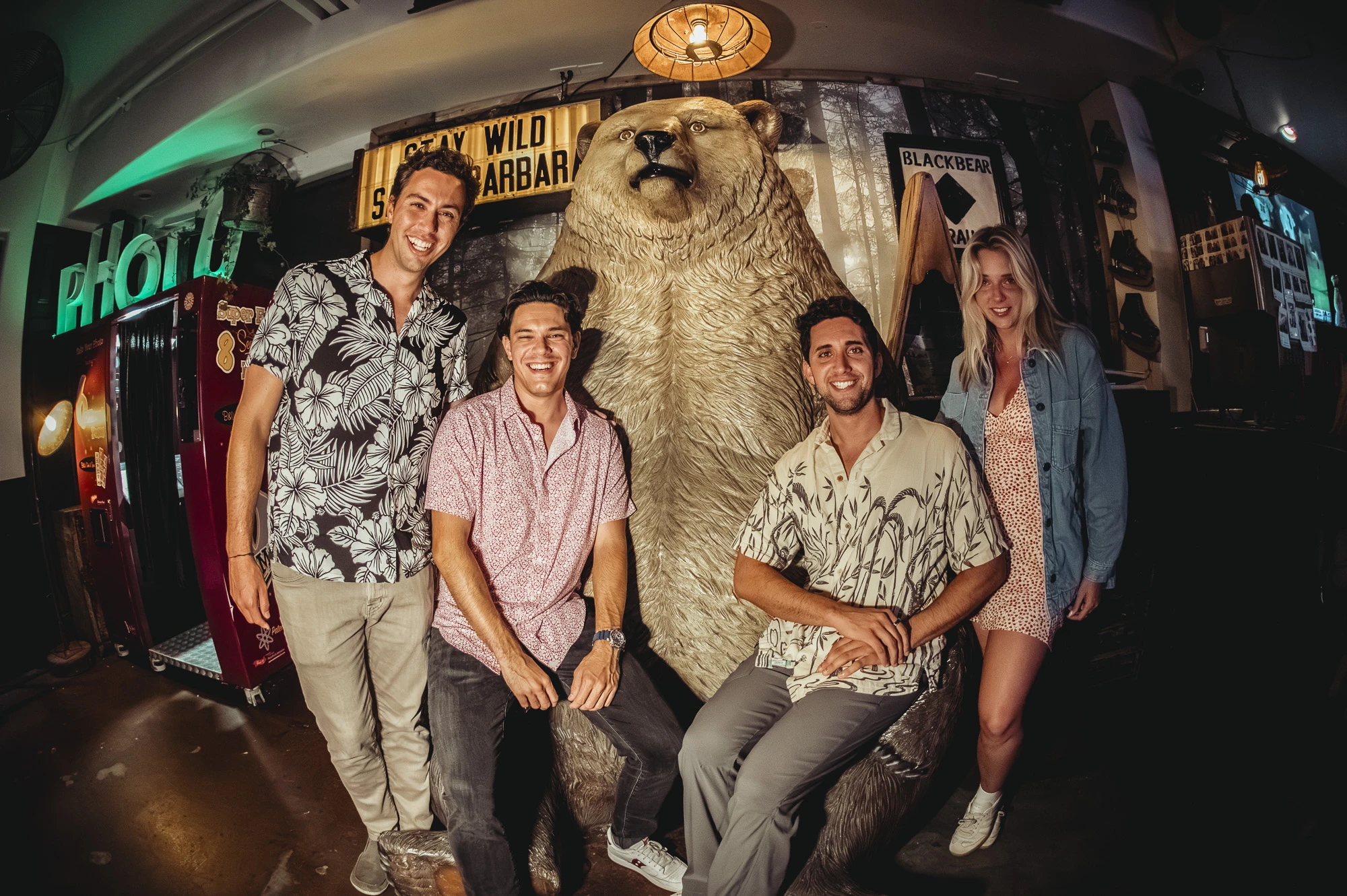 Group of friends posing and smiling with the iconic bear statue at Unbearable Skee Lodge
