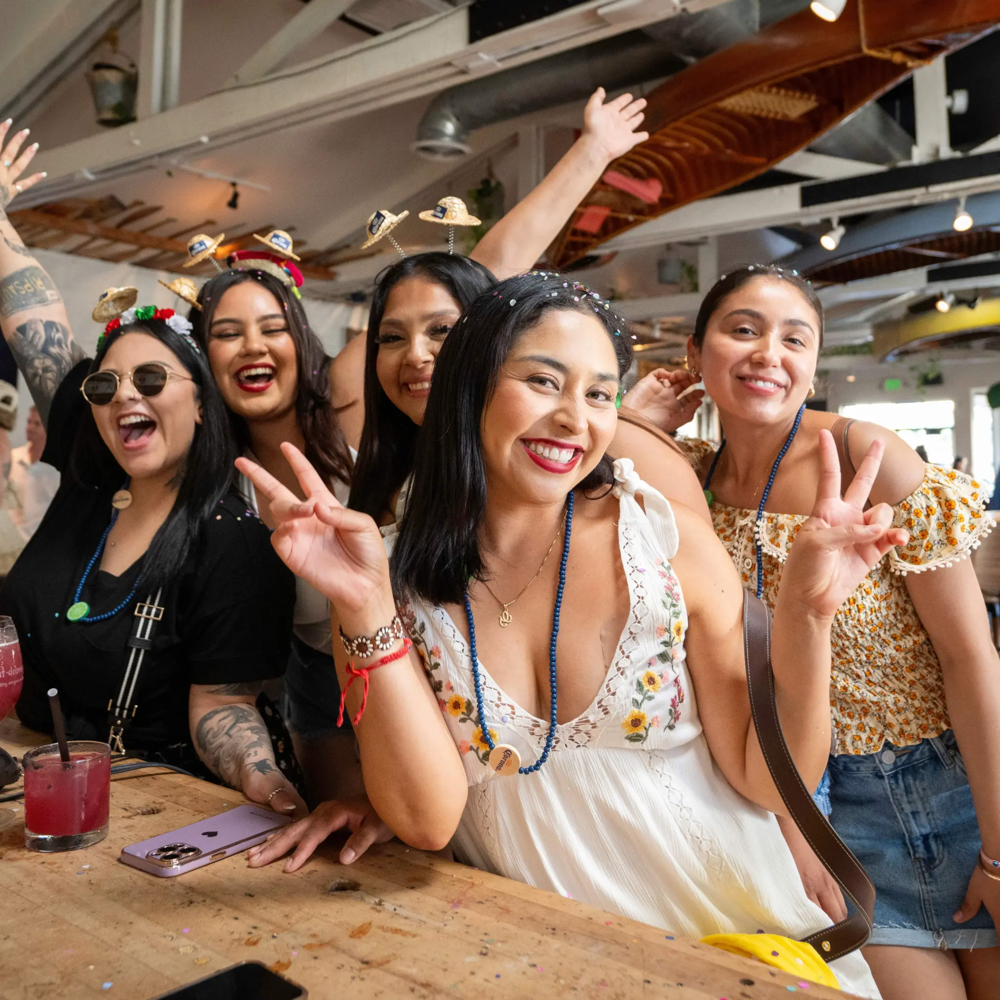 Group of women celebrating at Unbearable Skee Lodge wearing festive headbands and holding cocktails