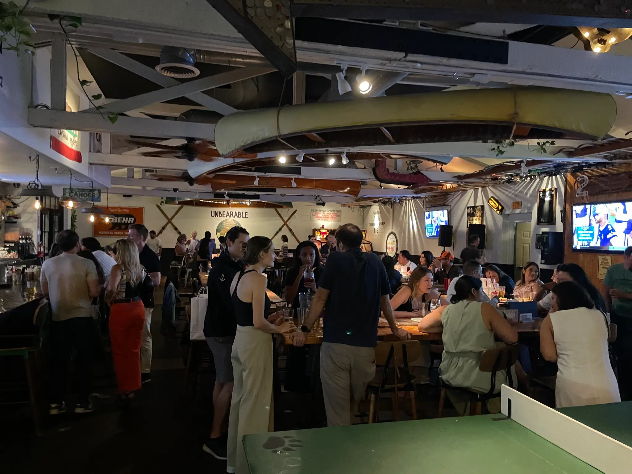 Packed crowd at Unbearable Skee Lodge during a work happy hour event with people mingling and drinks in hand