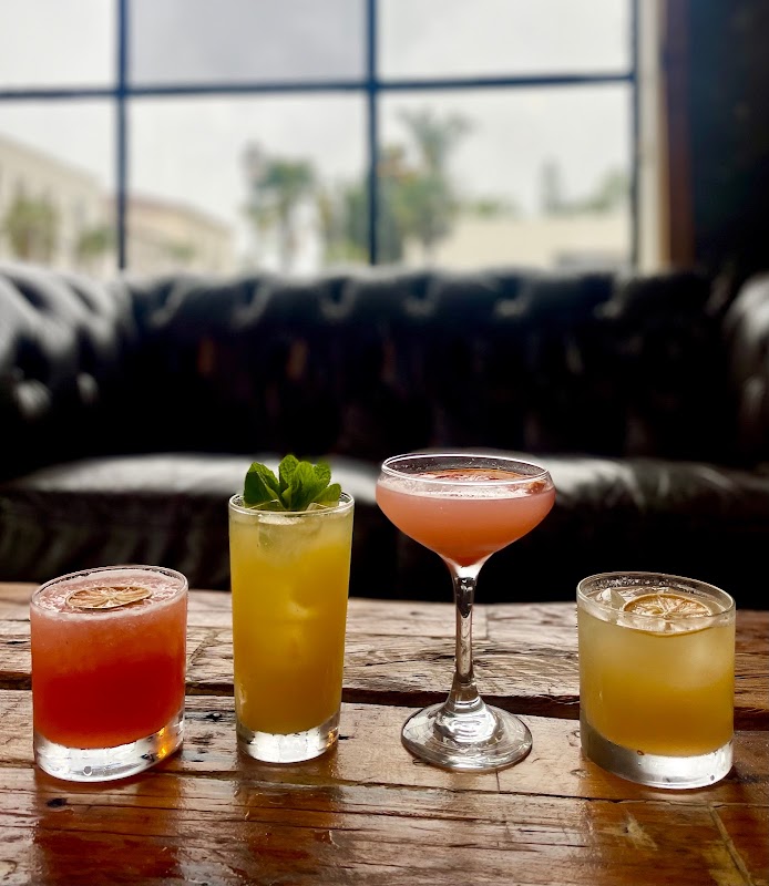 Four craft cocktails from Unbearable Skee Lodge on a rustic wooden table