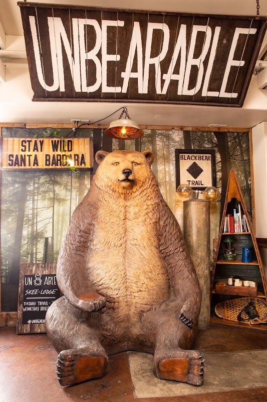 The iconic Unbearable Skee Lodge bear statue beneath the hand-painted UNBEARABLE sign, with Stay Wild Santa Barbara and Blackbear Trail signs in the background