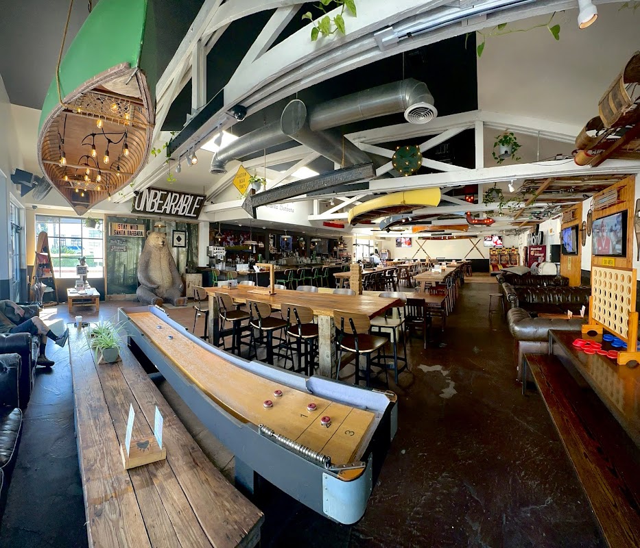 Wide-angle interior of Unbearable Skee Lodge showing the shuffleboard table, bar area, and full venue with vintage decor