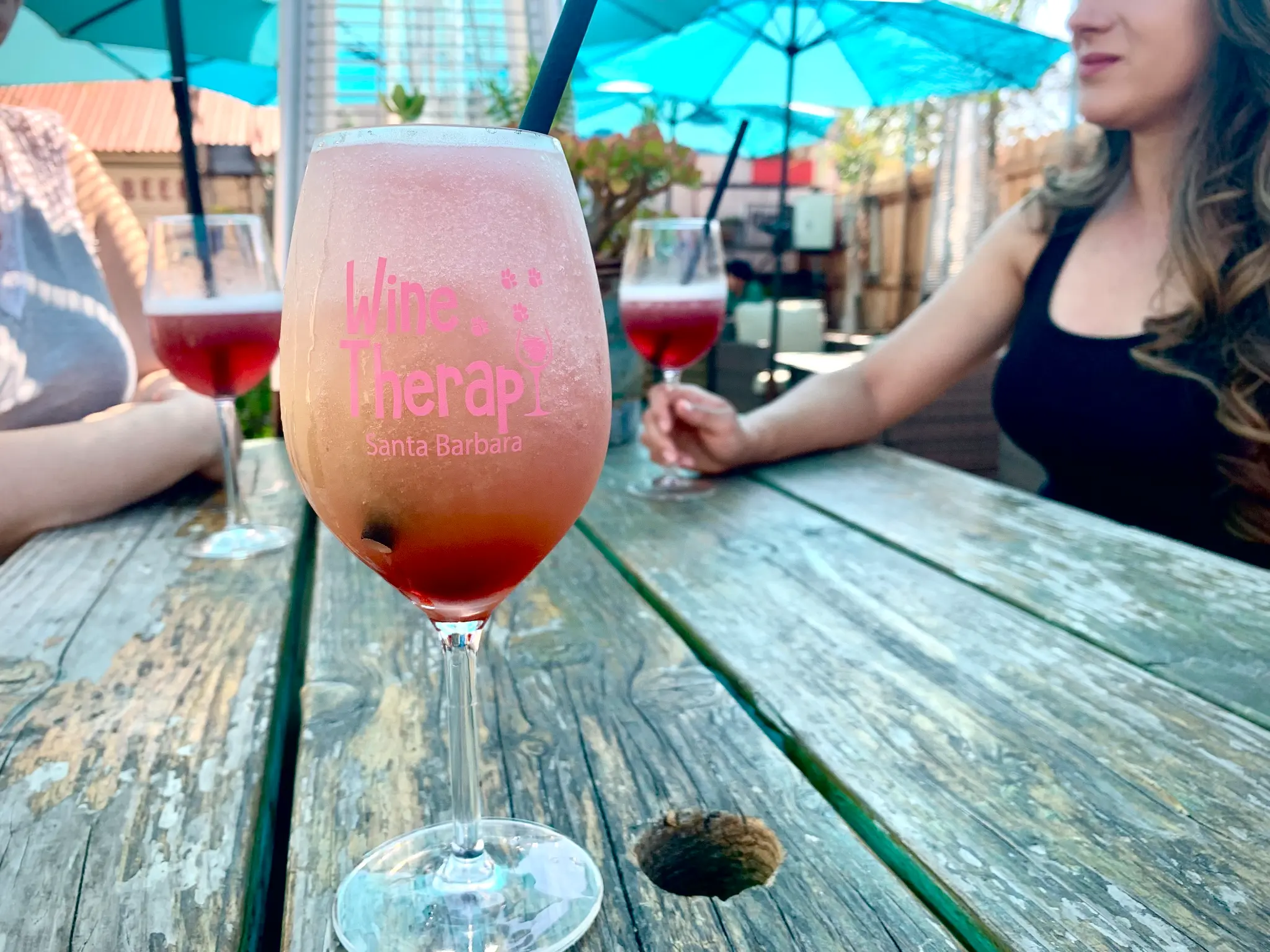 The Wine Therapy patio at Unbearable with palm trees, string lights, heaters, and picnic tables
